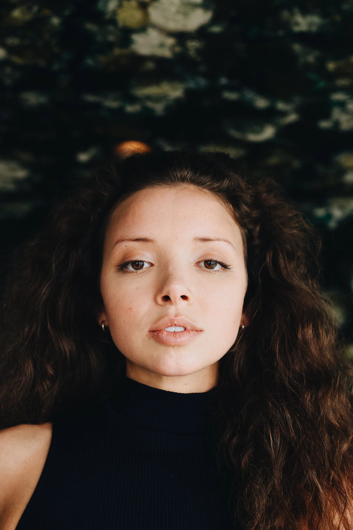Close portrait of a woman in a black top, looking directly into the camera